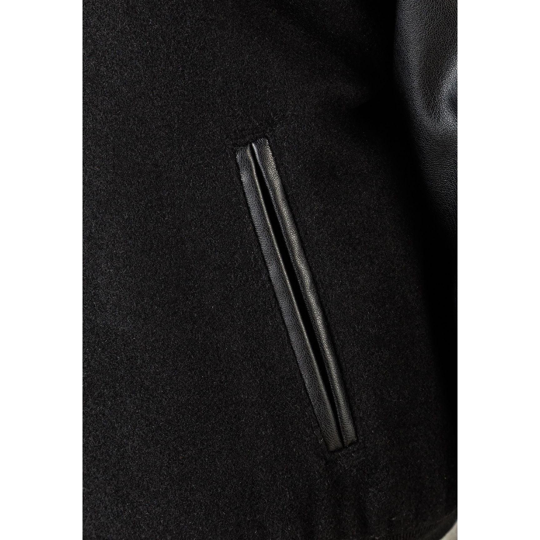 Close-up detail of black jacket showing side pocket with faux leather trim and felt body texture