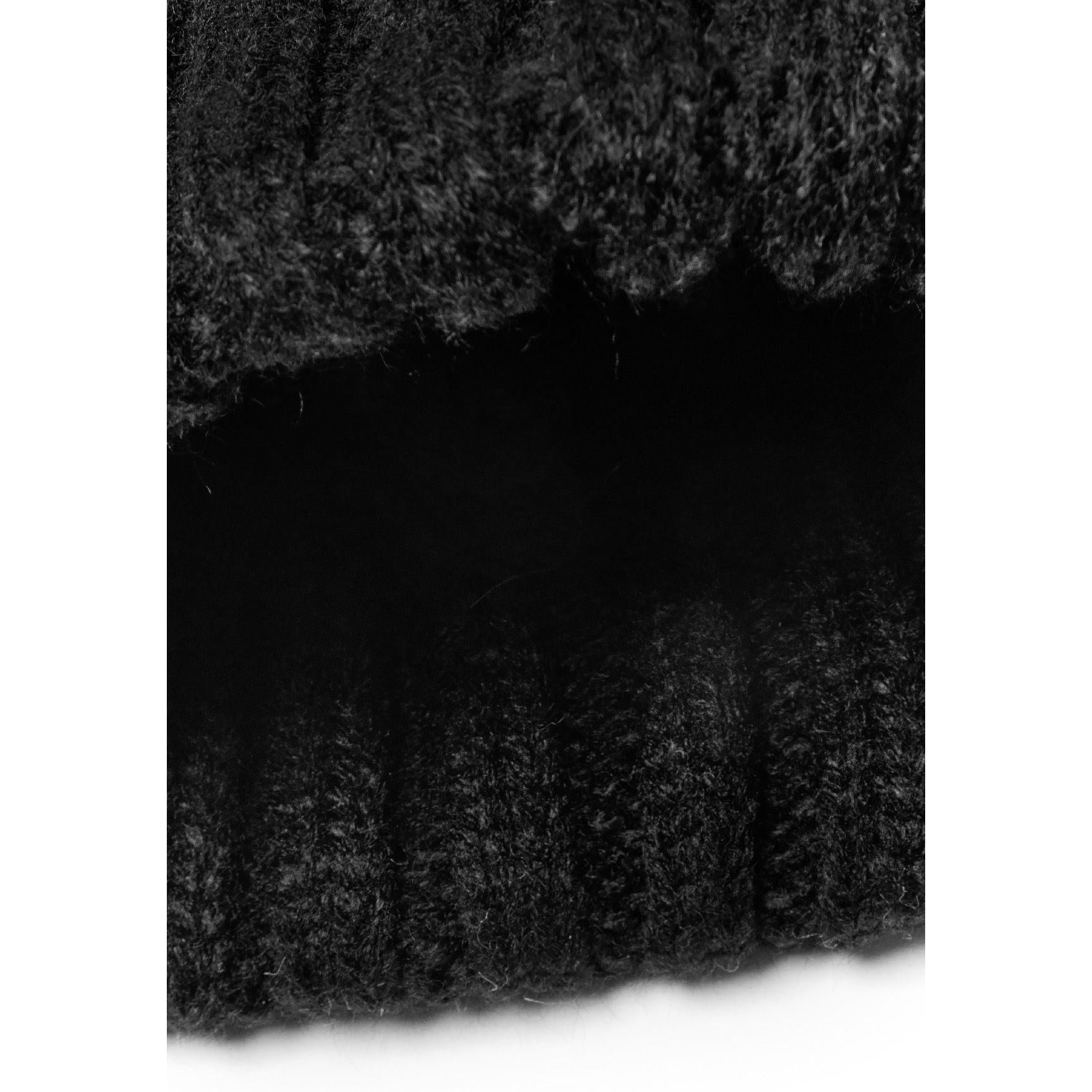 Interior view of black cable knit hat showing soft knitted lining and ribbed edge detail against white background