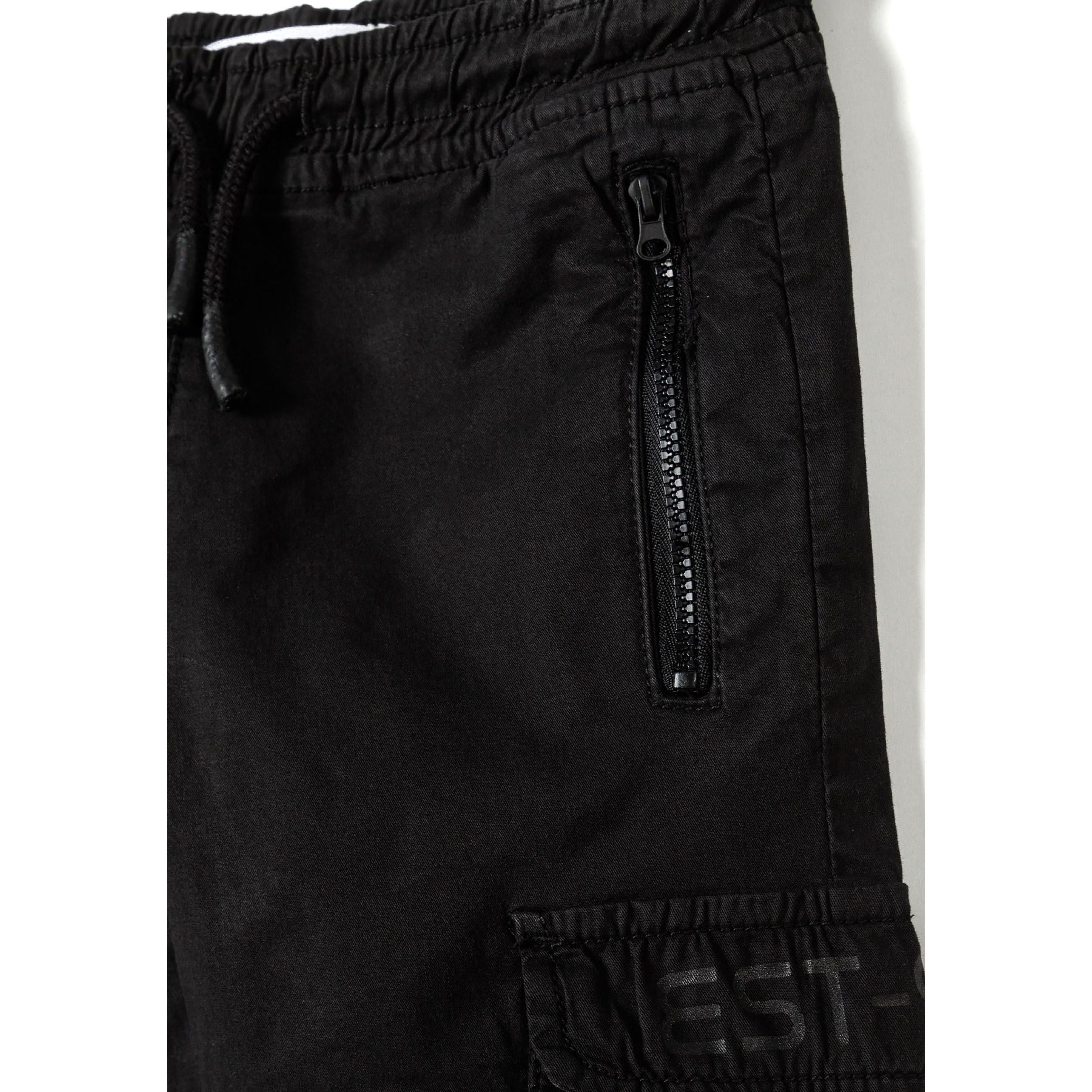 Close-up detail of black cargo pocket with zip closure and printed logo on side of trousers