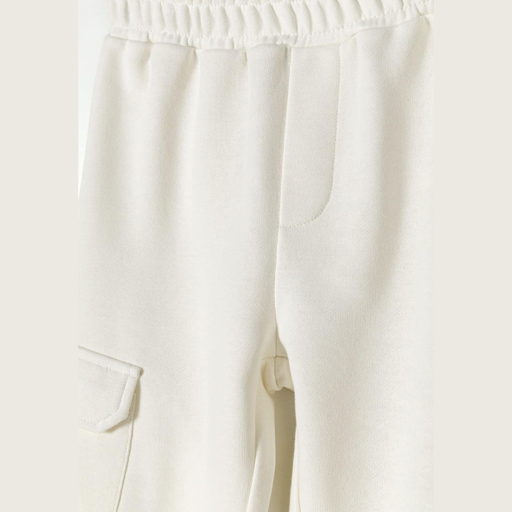 Close-up detail of white fleece fabric texture showing elastic waistband with drawstring and cargo pocket construction