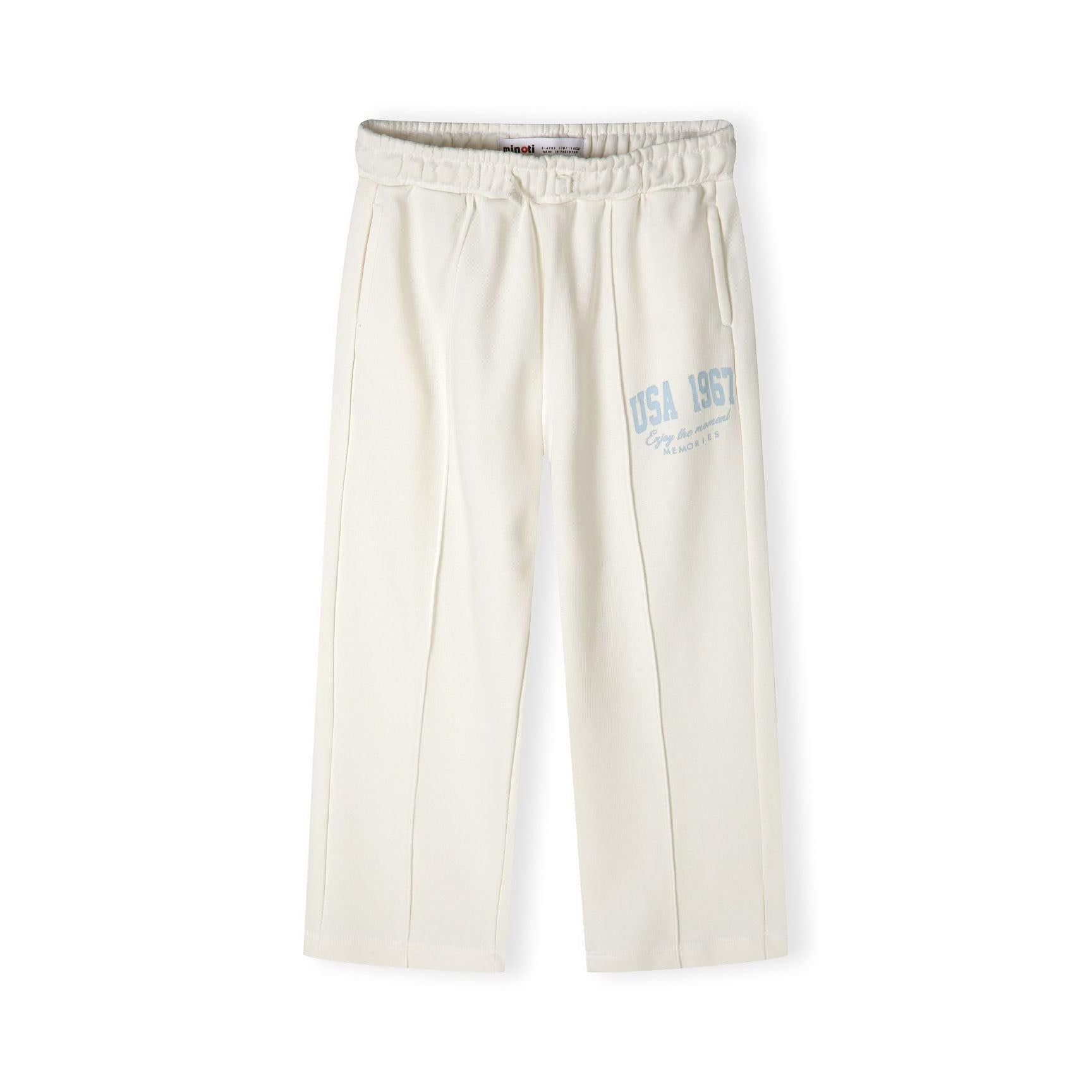 Close-up detail of cream joggers showing blue vintage-style text print reading 'USA 1967' with memories script text