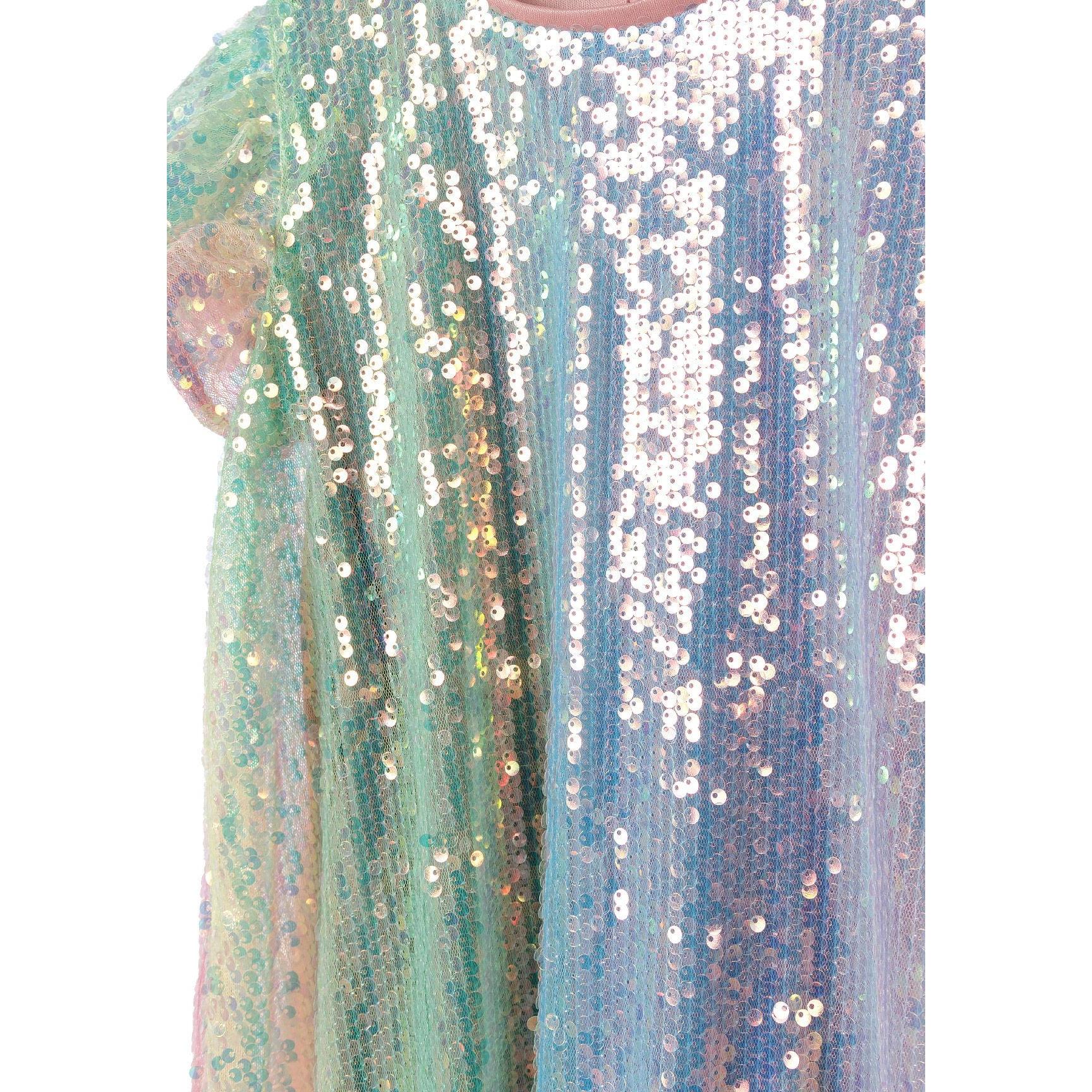 Close-up detail of multicolour sequin fabric showing individual sequins in rainbow ombre effect from green to purple