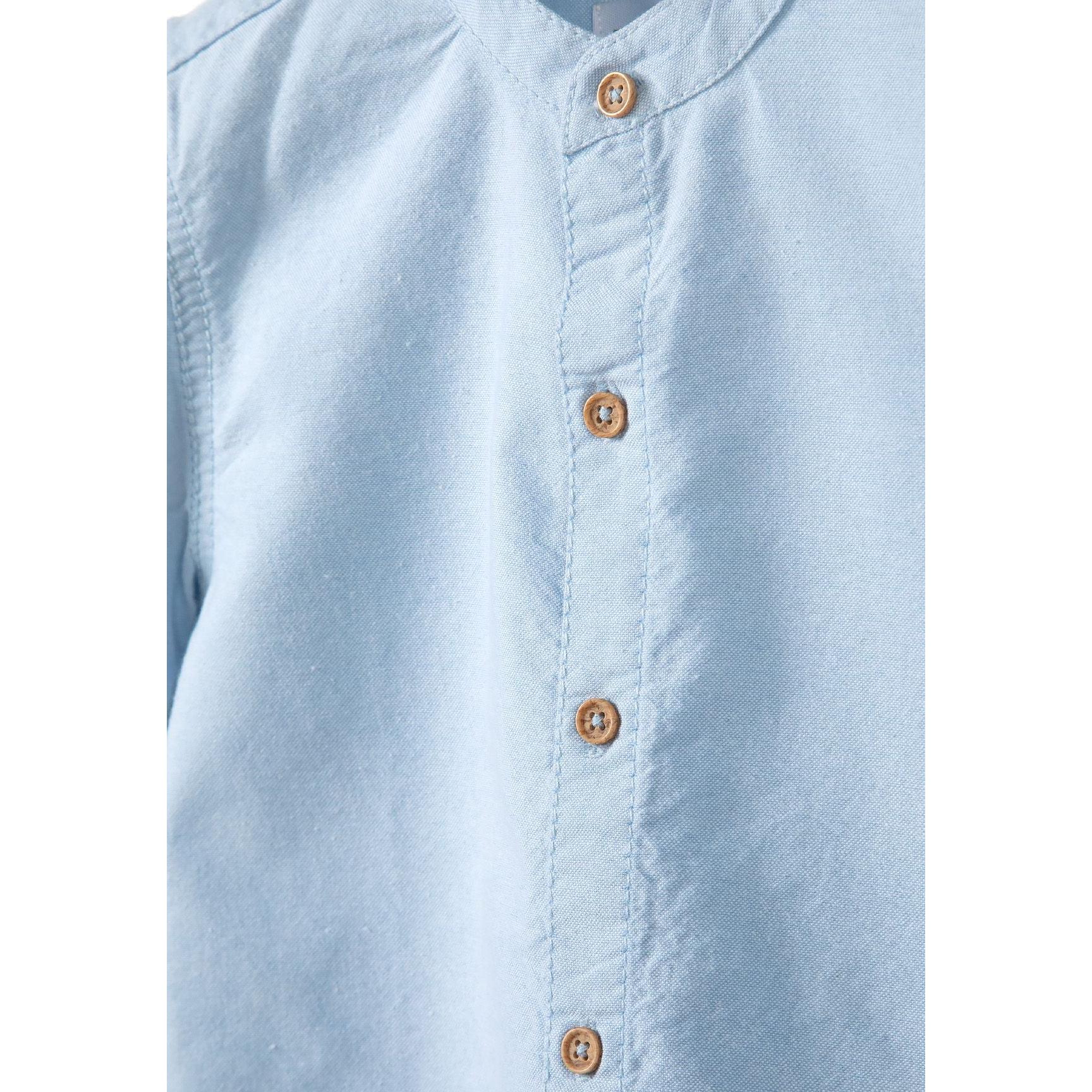 Close-up detail of navy shorts showing adjustable waistband with brown button and pocket construction