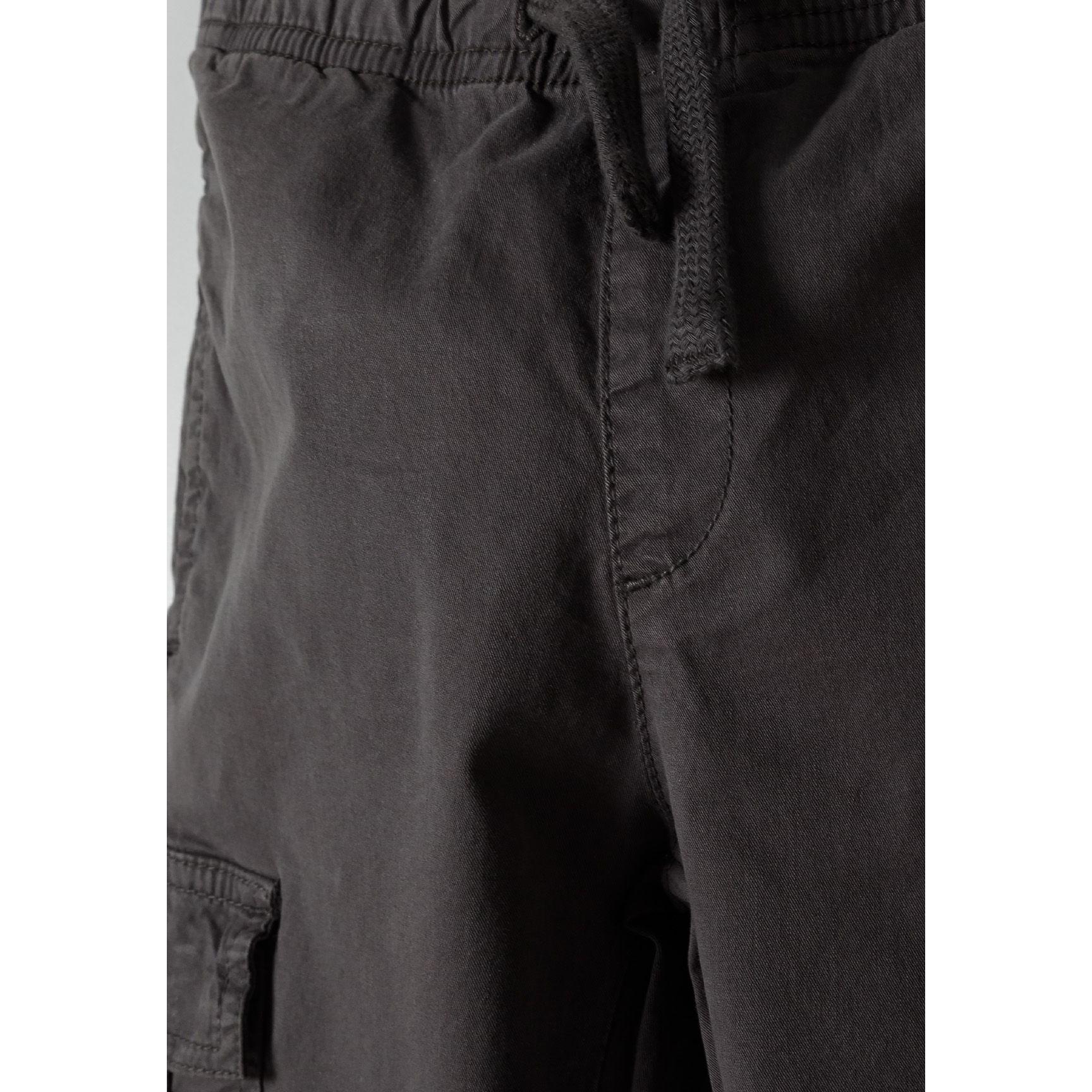 Close-up detail of grey cargo trousers showing elasticated waistband with drawstring and cargo pocket construction