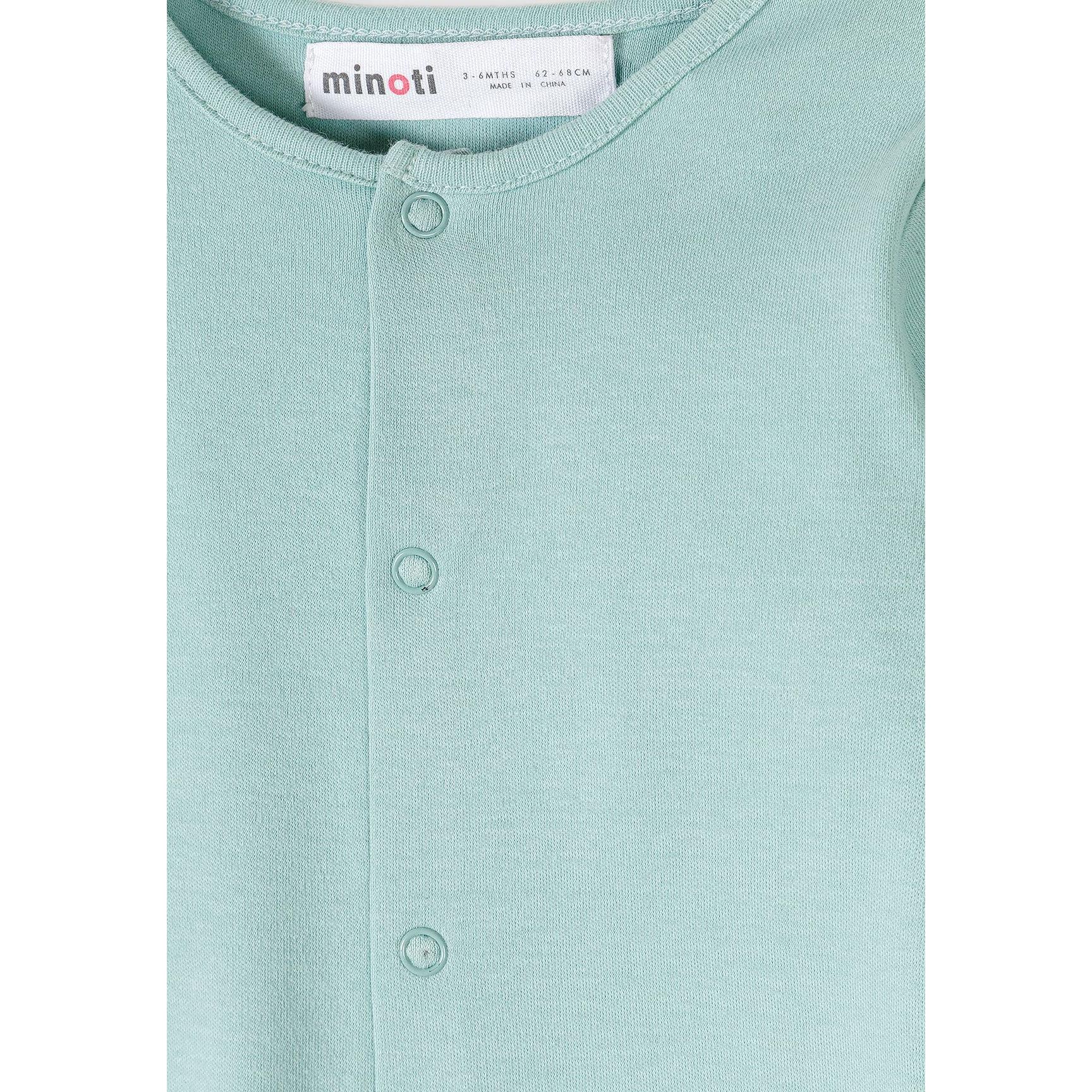 Close-up detail of mint green sleepsuit showing snap button fastenings and Minoti brand label at the neckline with soft jersey fabric texture visible