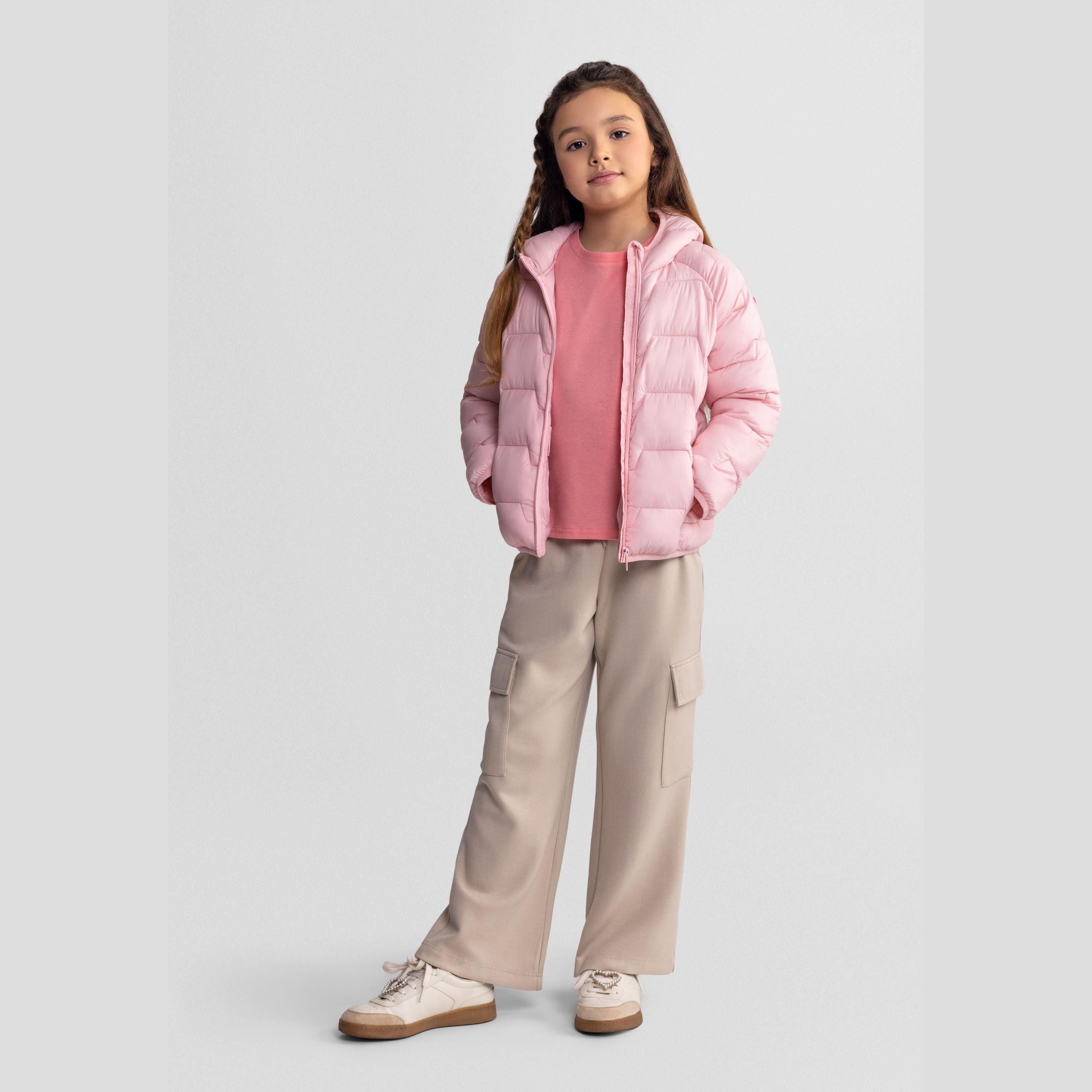 Girl wearing beige wide leg joggers with cargo pockets, pink puffer jacket and pink top, standing against white background with hands at sides