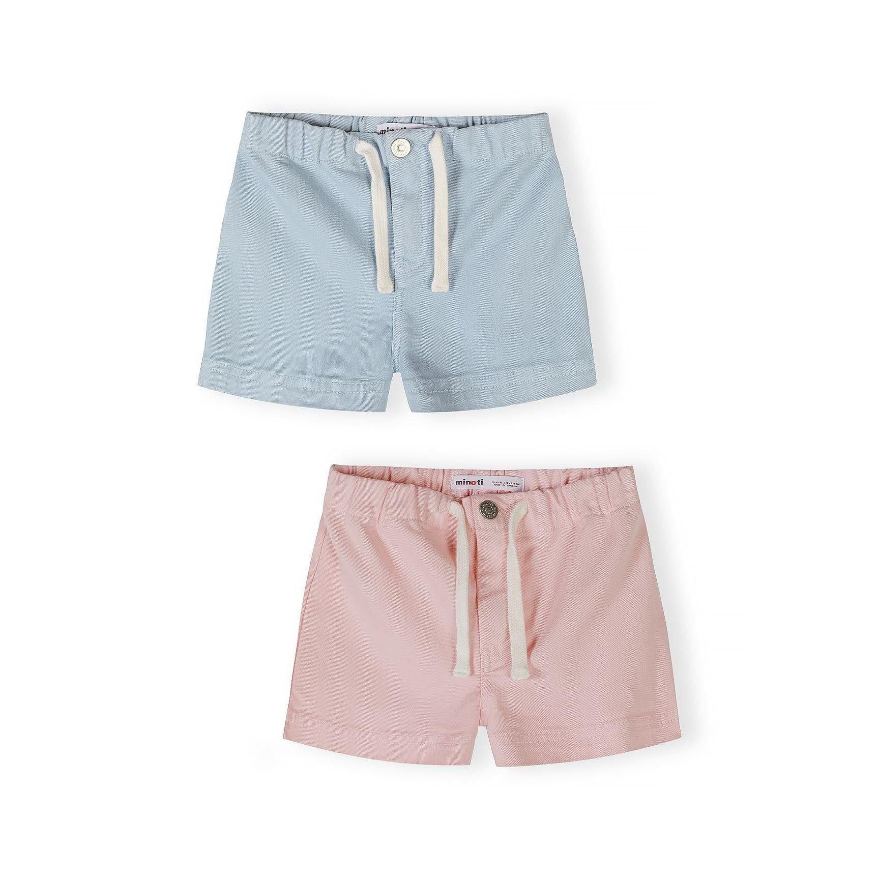 Two pairs of Minoti twill shorts displayed flat - light blue pair on top and soft pink pair below, both featuring white drawstring ties and button fastenings on white background