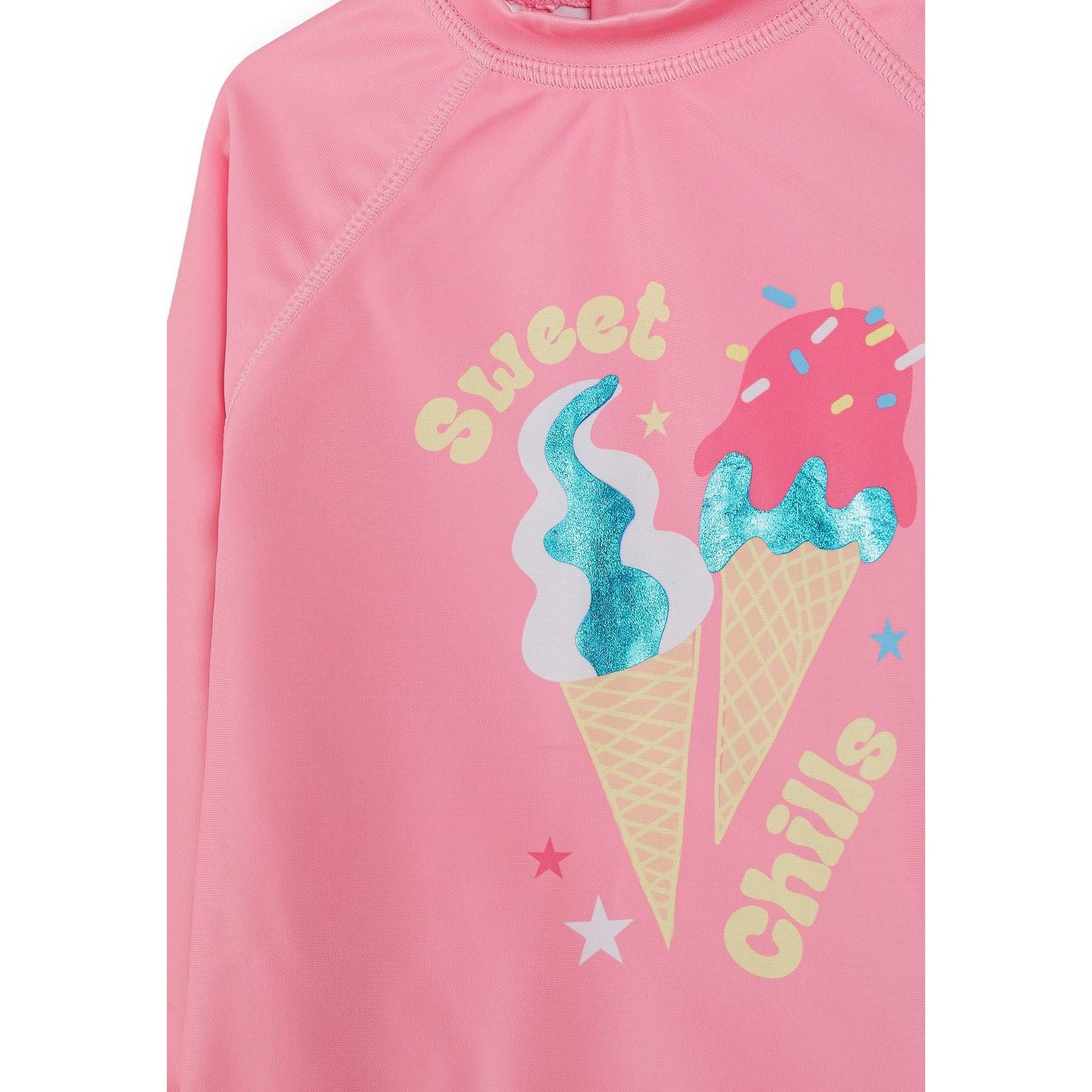 Detail shot of pink rash vest showing Sweet and Chill text with colorful ice cream cone graphics featuring glitter accents
