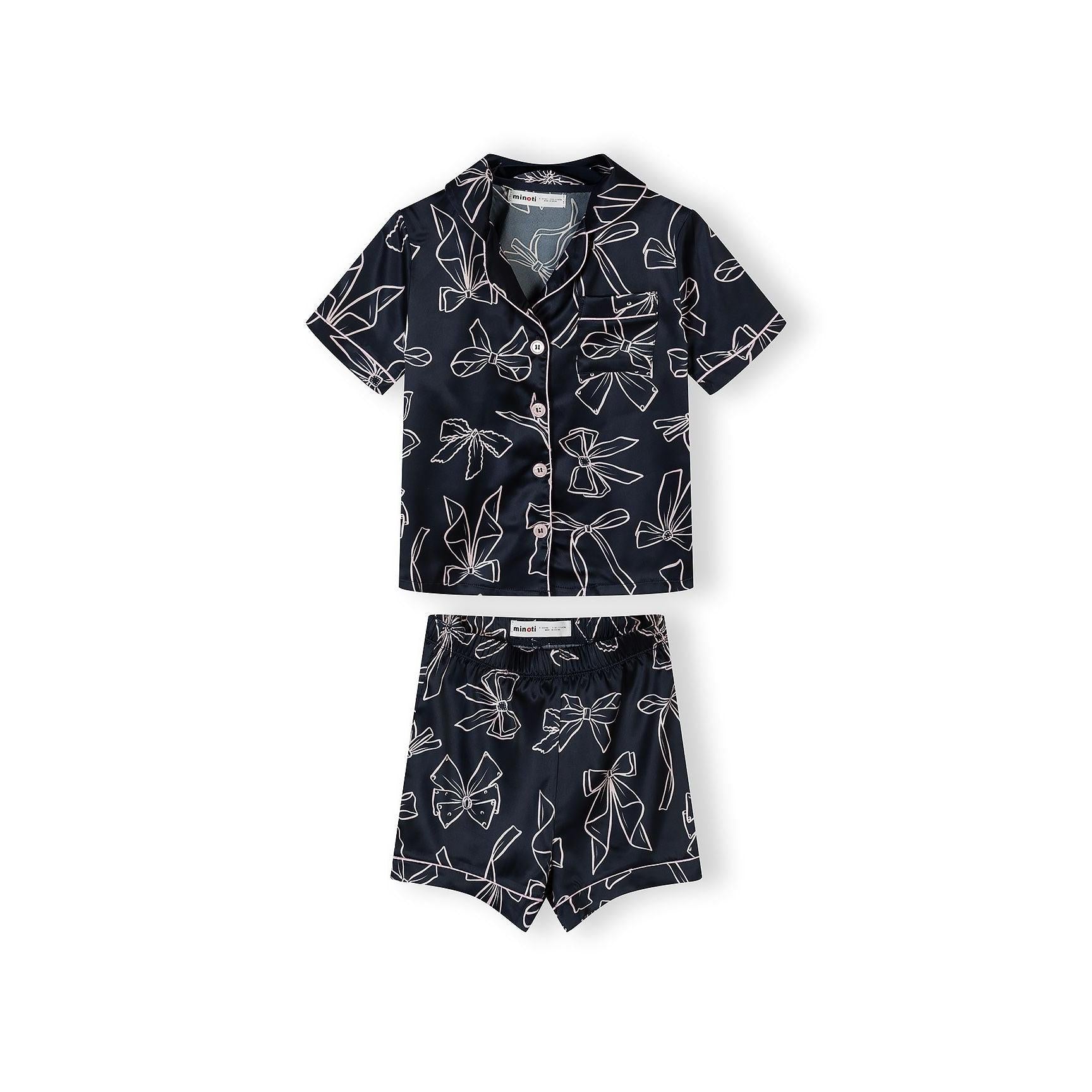 Navy satin pyjama set with white bow print laid flat on white background, showing button-front top and matching shorts