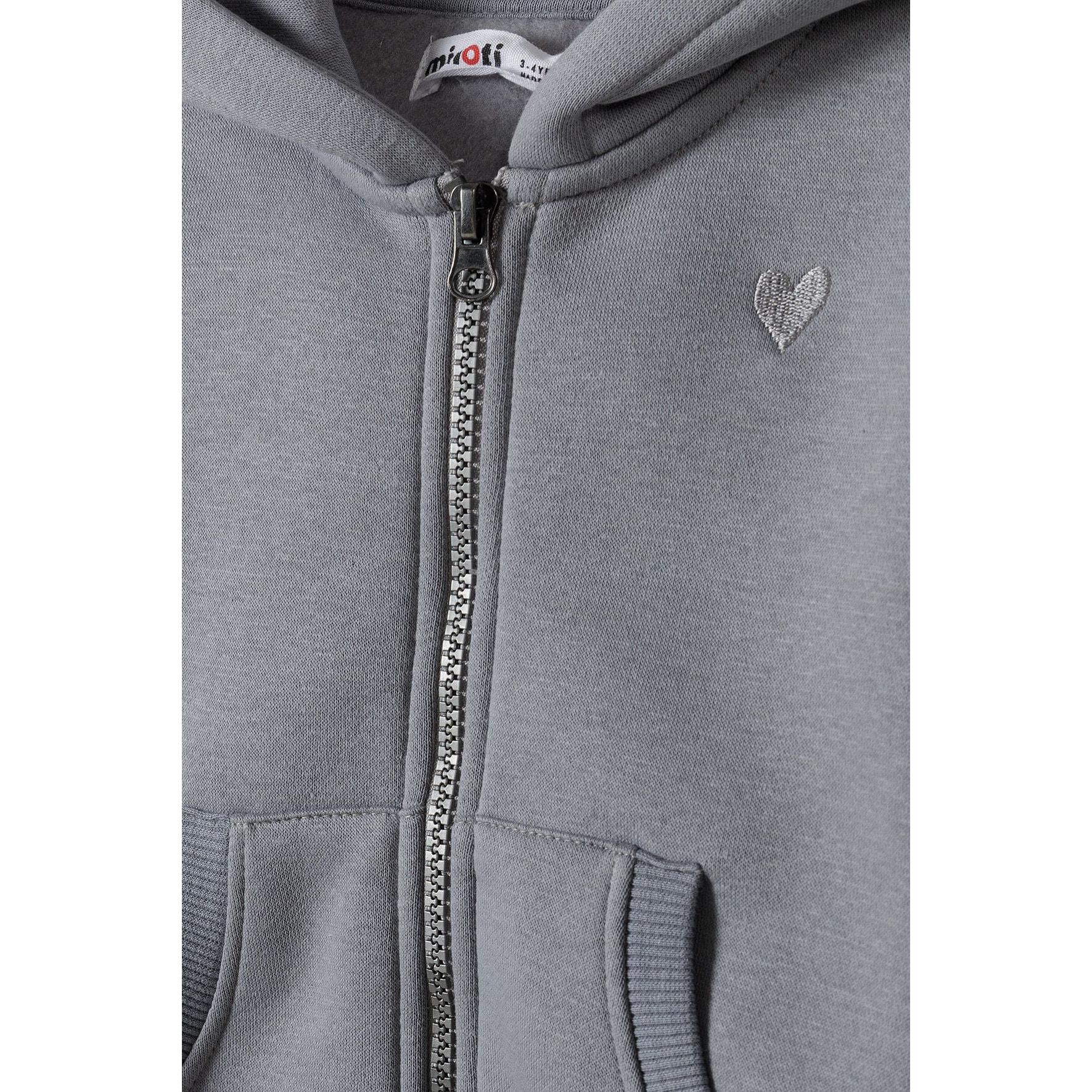 Close-up detail of grey fleece hoodie showing front zip, Minoti label, embroidered heart detail and kangaroo pocket