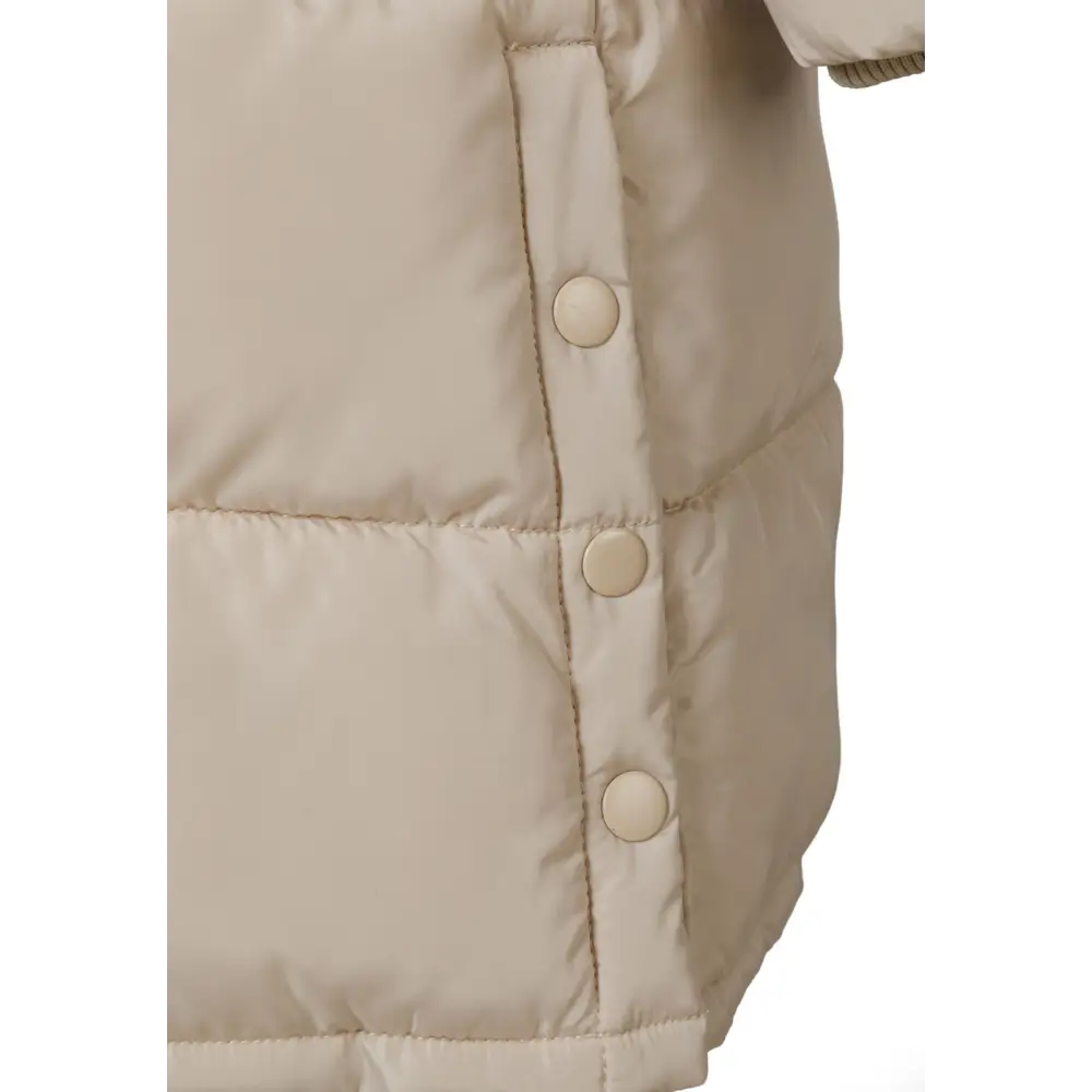 Close-up detail of beige parka jacket showing quilted texture, snap button closures and padded construction