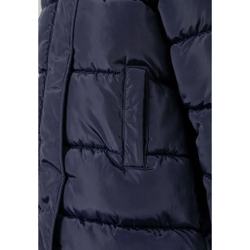 Close-up detail of navy quilted parka showing front pocket, zip closure and quilted padding texture