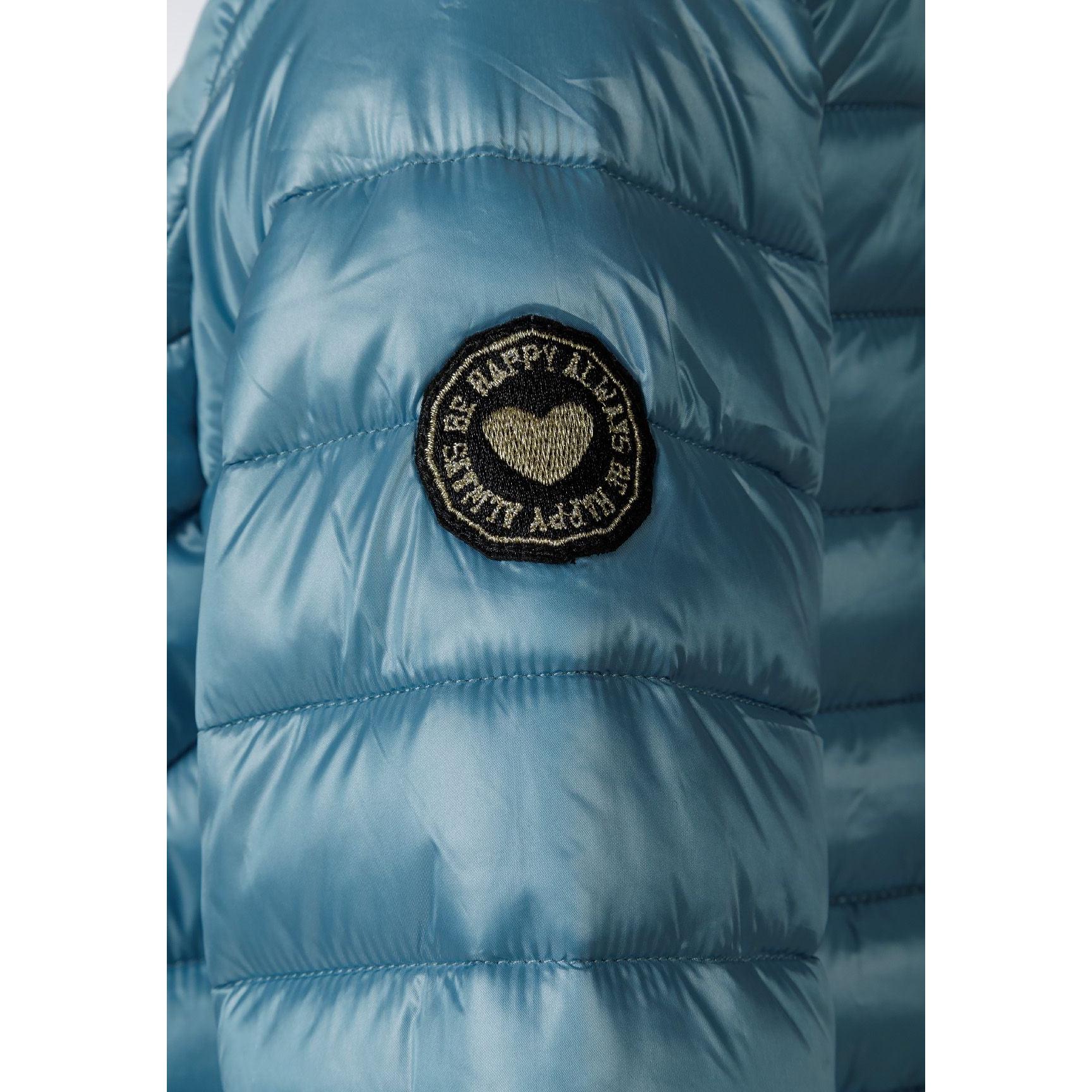 Close-up detail of circular embroidered patch with heart design on turquoise quilted fabric