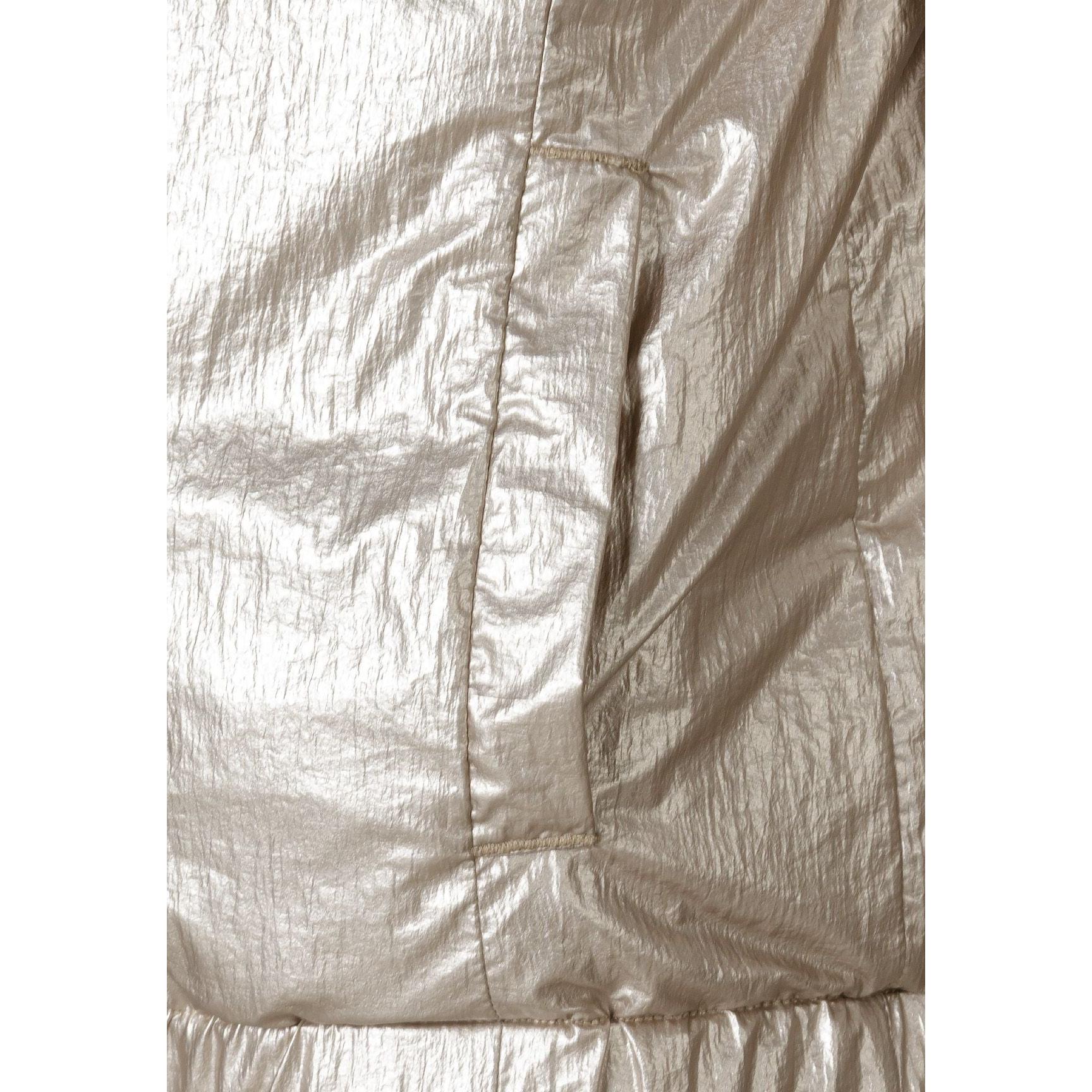 Close-up detail of beige metallic quilted fabric texture showing diamond pattern stitching and shiny surface finish