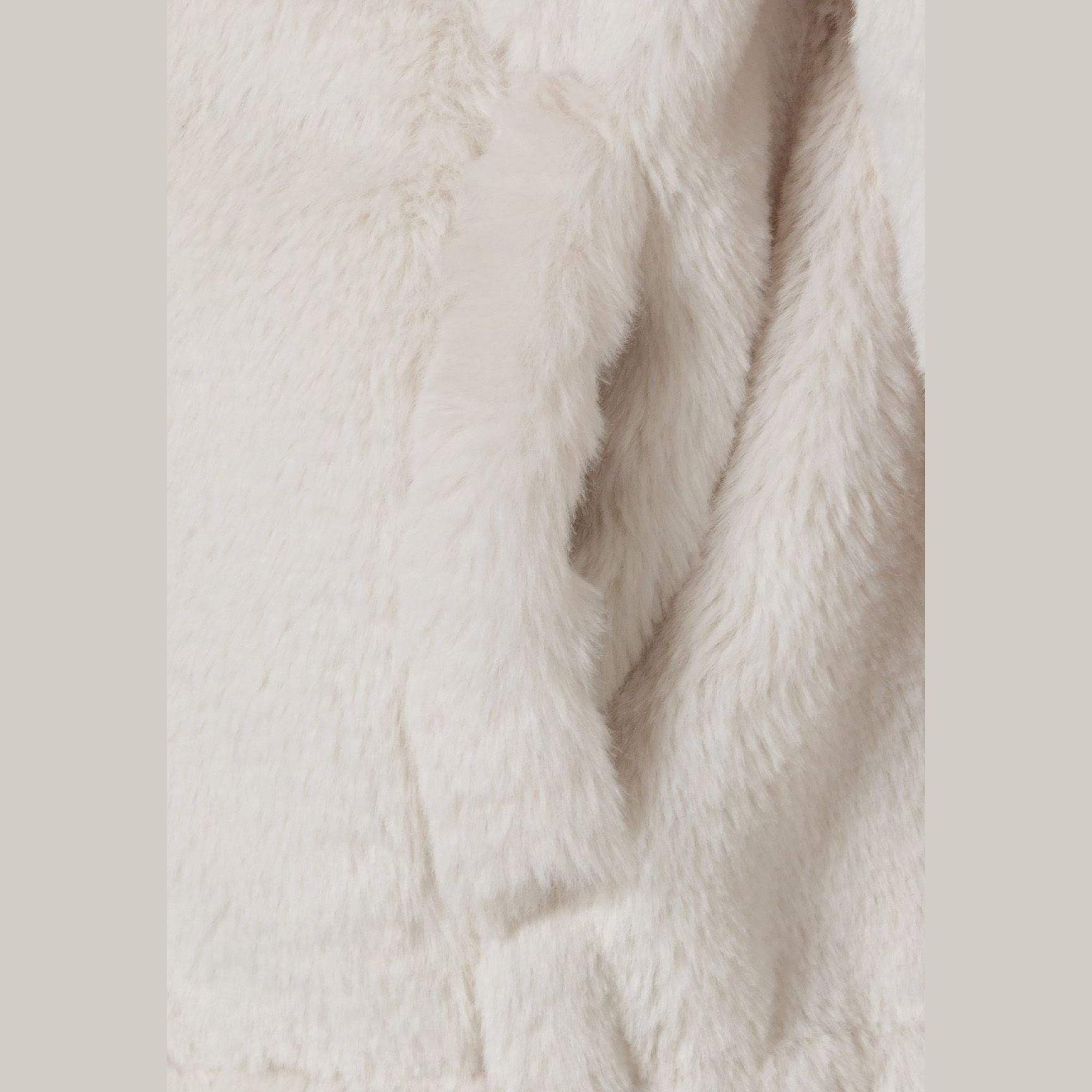 Close-up of cream teddy fur fabric texture showing soft fluffy pile and plush finish of jacket interior