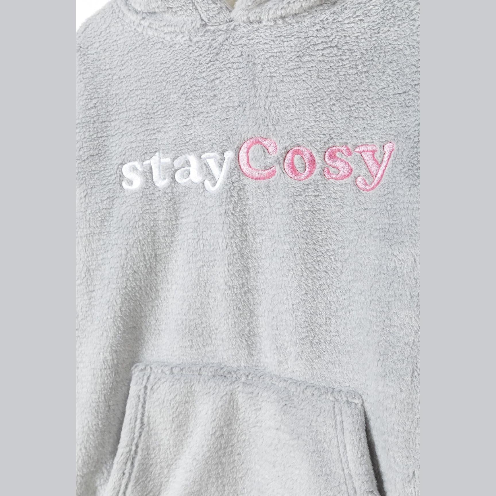 Close-up detail of embroidered 'Stay Cosy' text in white and pink lettering on grey teddy fleece fabric with kangaroo pocket visible