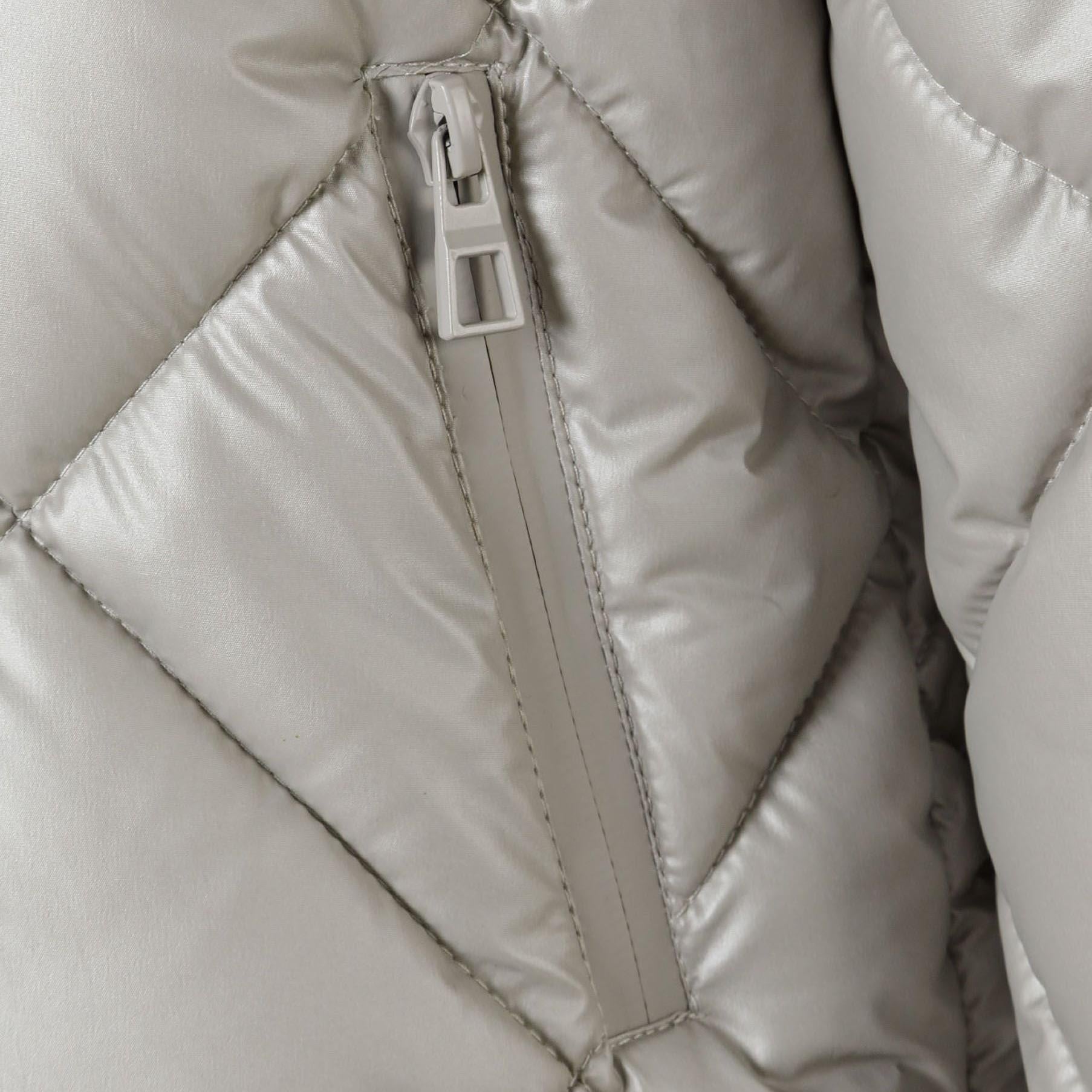 Close-up detail of silver quilted jacket showing full-zip closure and diamond quilting pattern texture