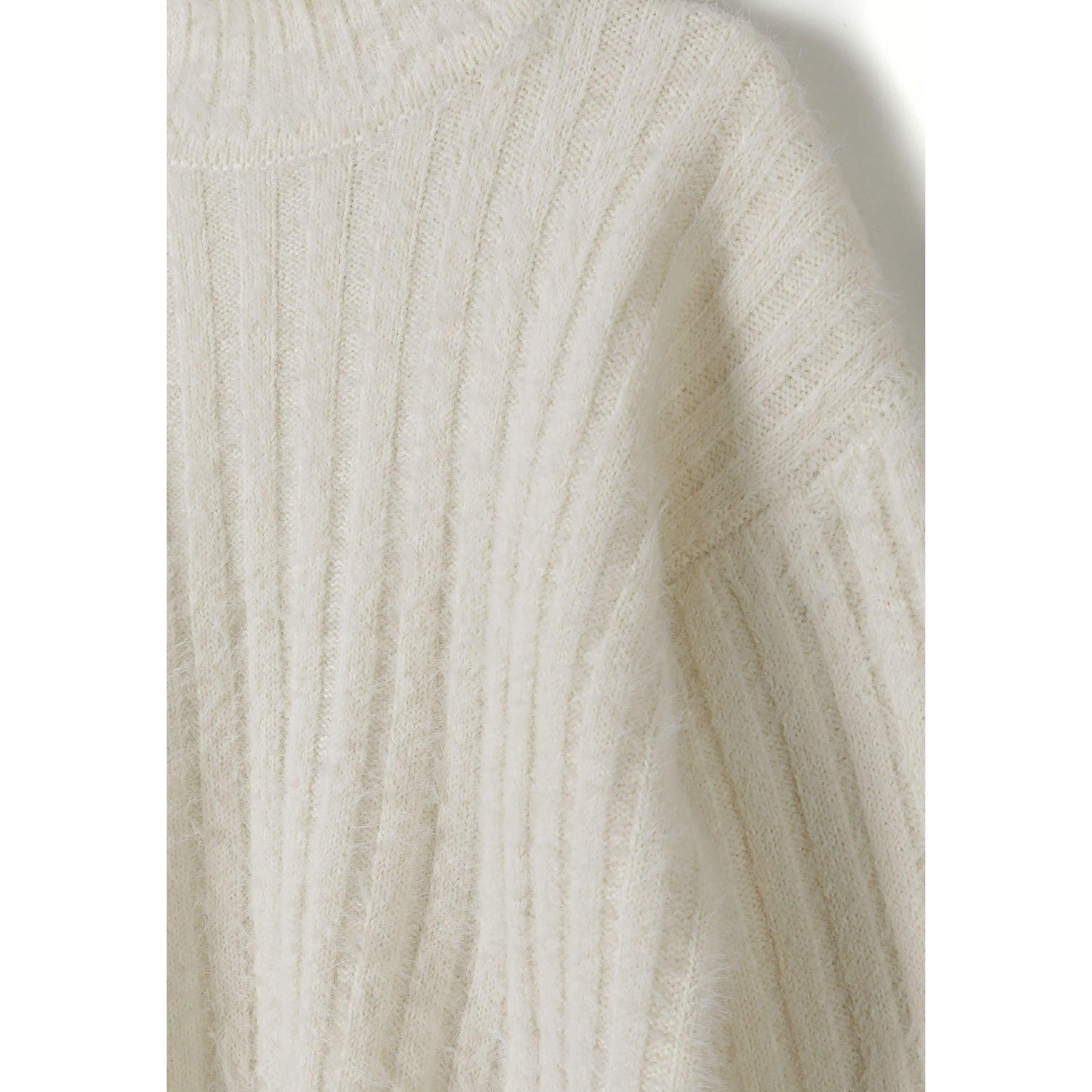 Close-up detail of cream ribbed knit texture showing soft vertical rib pattern and cosy fabric structure