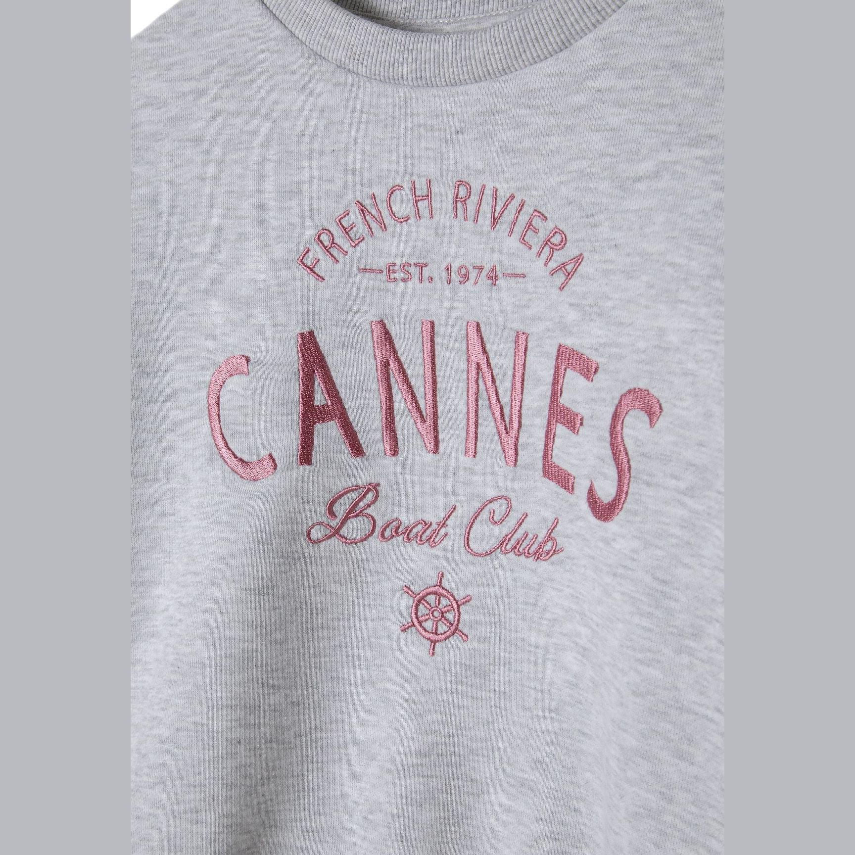 Close-up detail of pink French Riviera Cannes Boat Club EST. 1974 print with nautical wheel design on grey fleece fabric