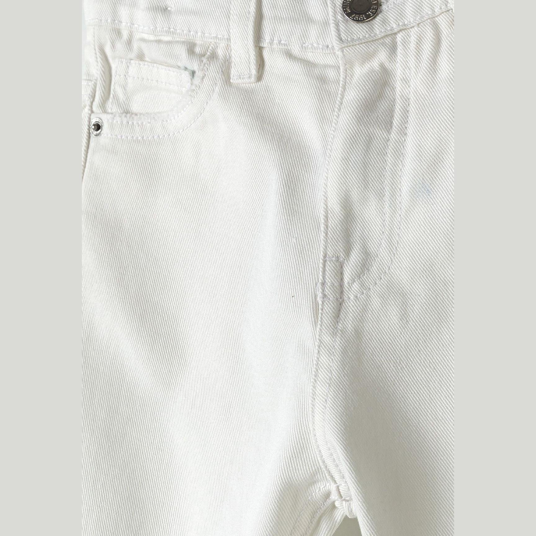 Close-up detail of white twill trousers showing front pocket, waistband and button fastening