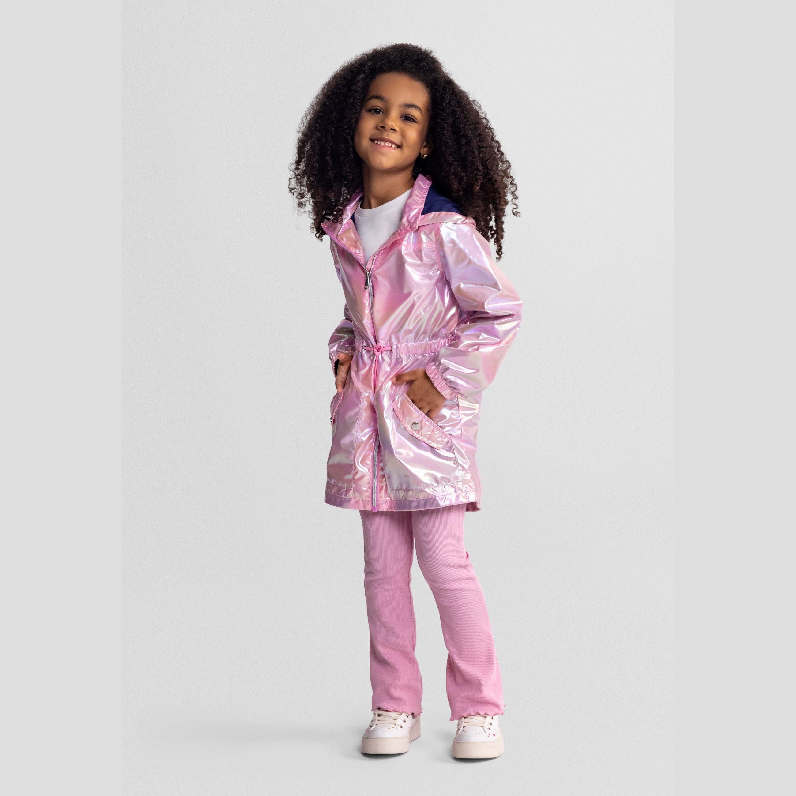 Same girl smiling in the pink shimmery jacket with hands on hips, showing full outfit including pink trousers and white trainers