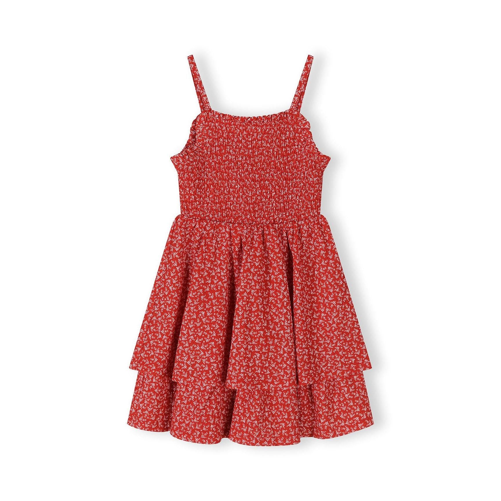Flat lay of red floral sleeveless dress showing shirred bodice construction and adjustable straps against white background