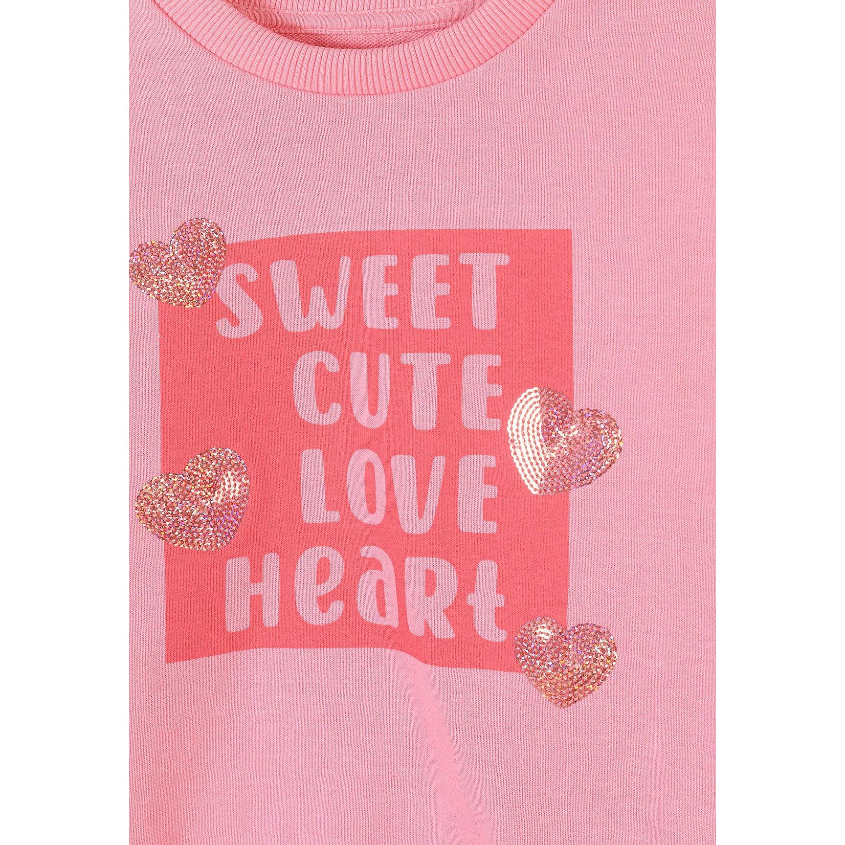 Close-up detail of pink sweatshirt front showing 'Sweet Cute Love Heart' text print in coral rectangle with sequined heart embellishments scattered around