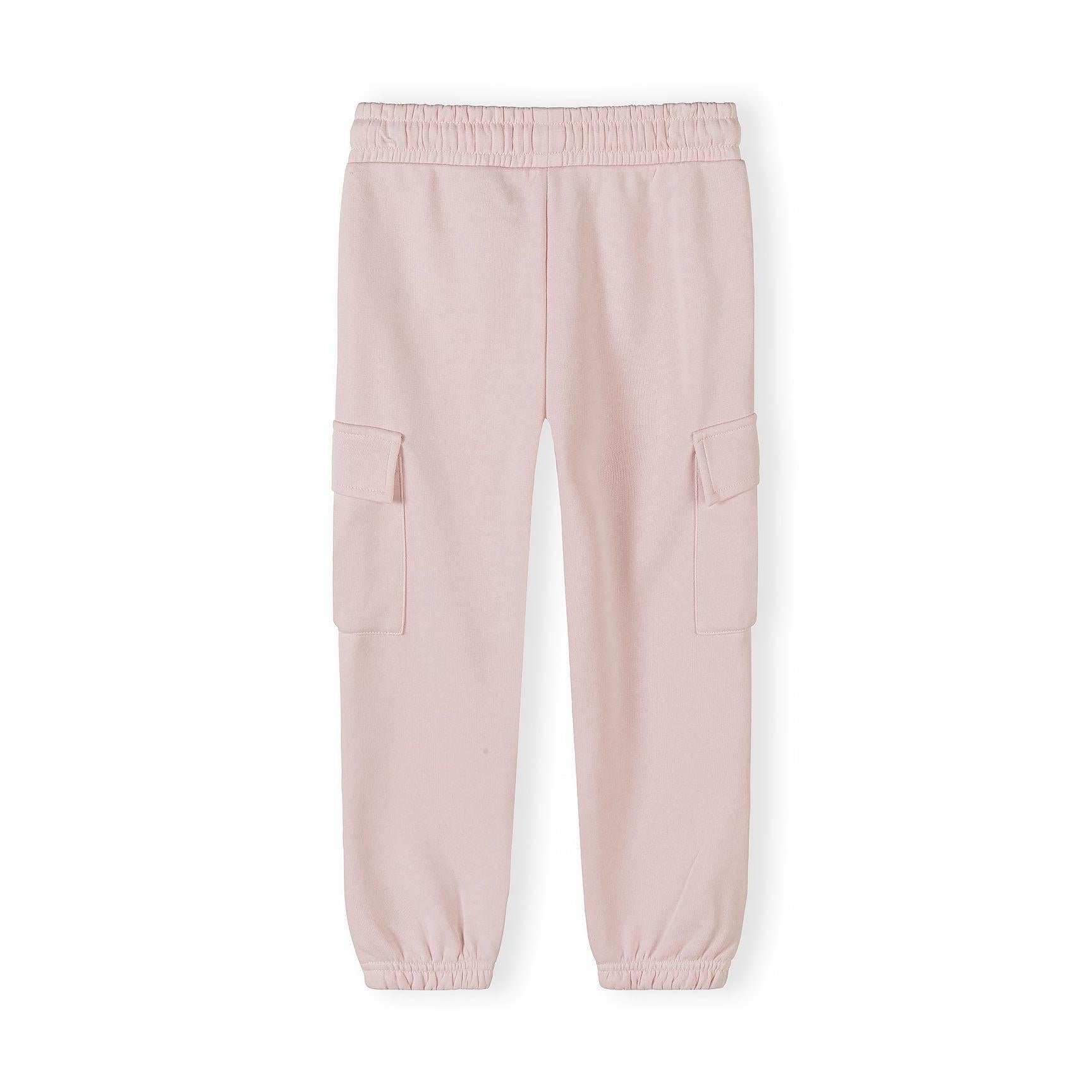 Close-up detail of light pink joggers waistband showing Minoti size label, elasticated waist with white drawstring ties, and fabric texture on pink background