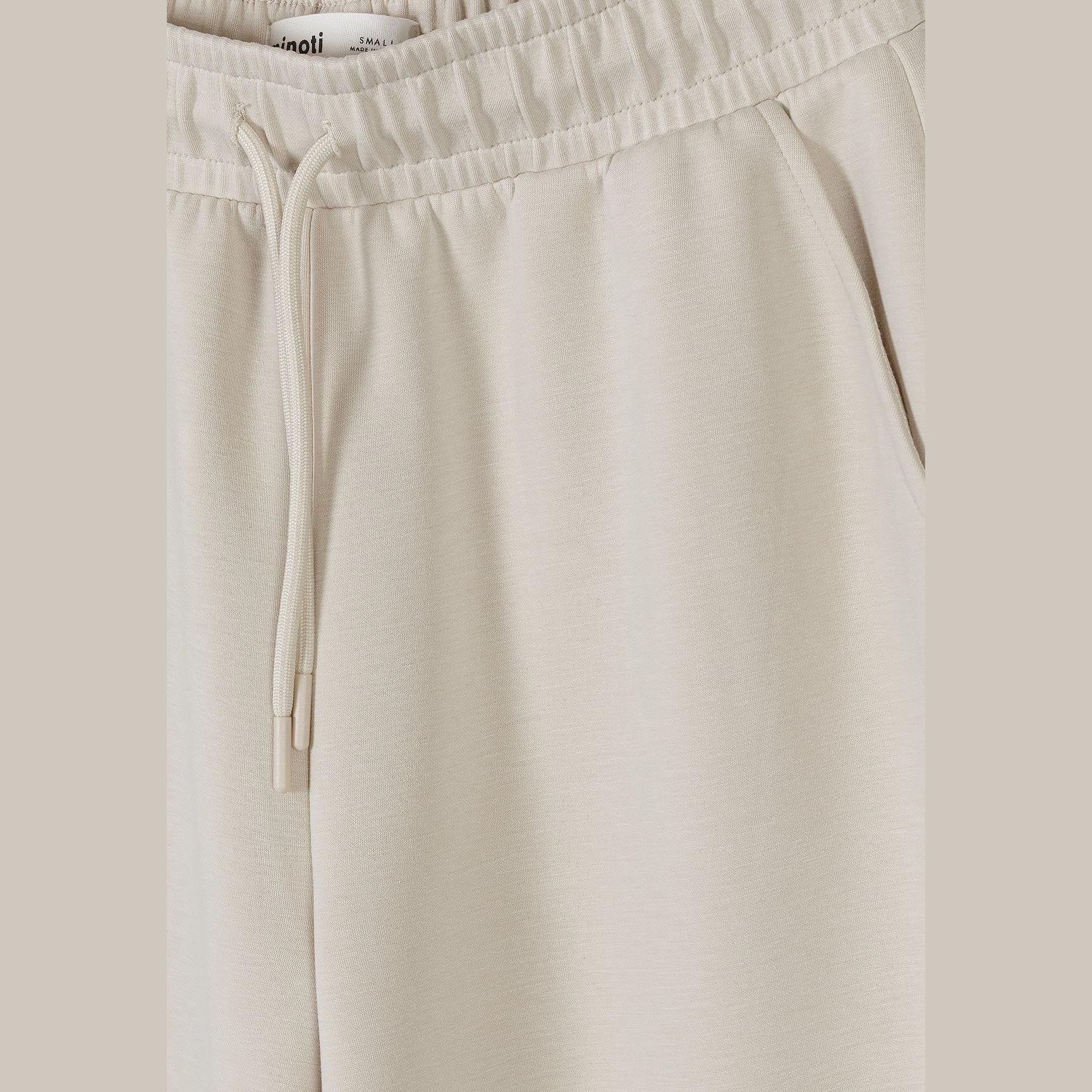 Close up detail of beige joggers showing Minoti label at waistband and soft viscose fabric texture with drawstring