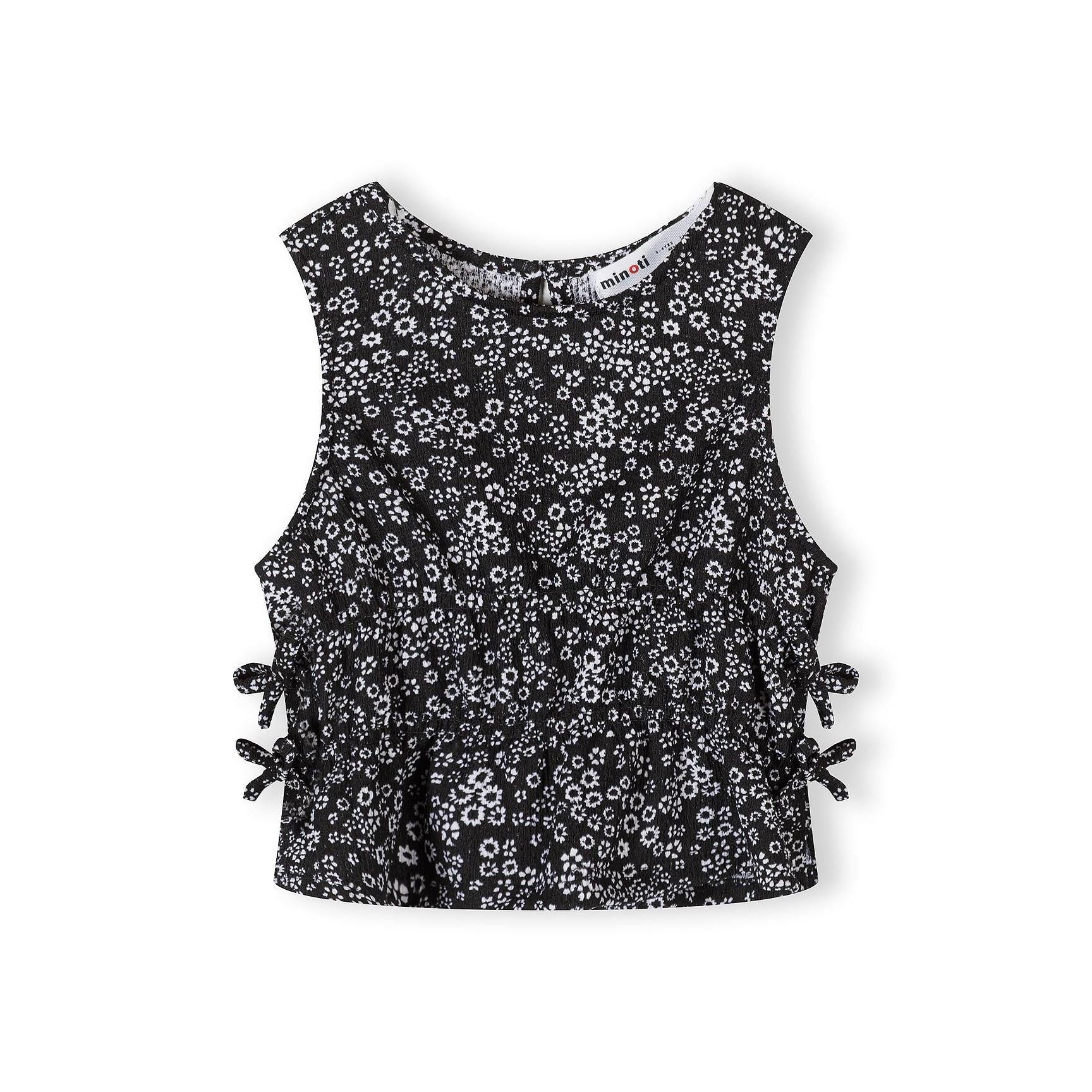 Close-up view of black wide-leg trousers with delicate white floral pattern, displayed flat on white background