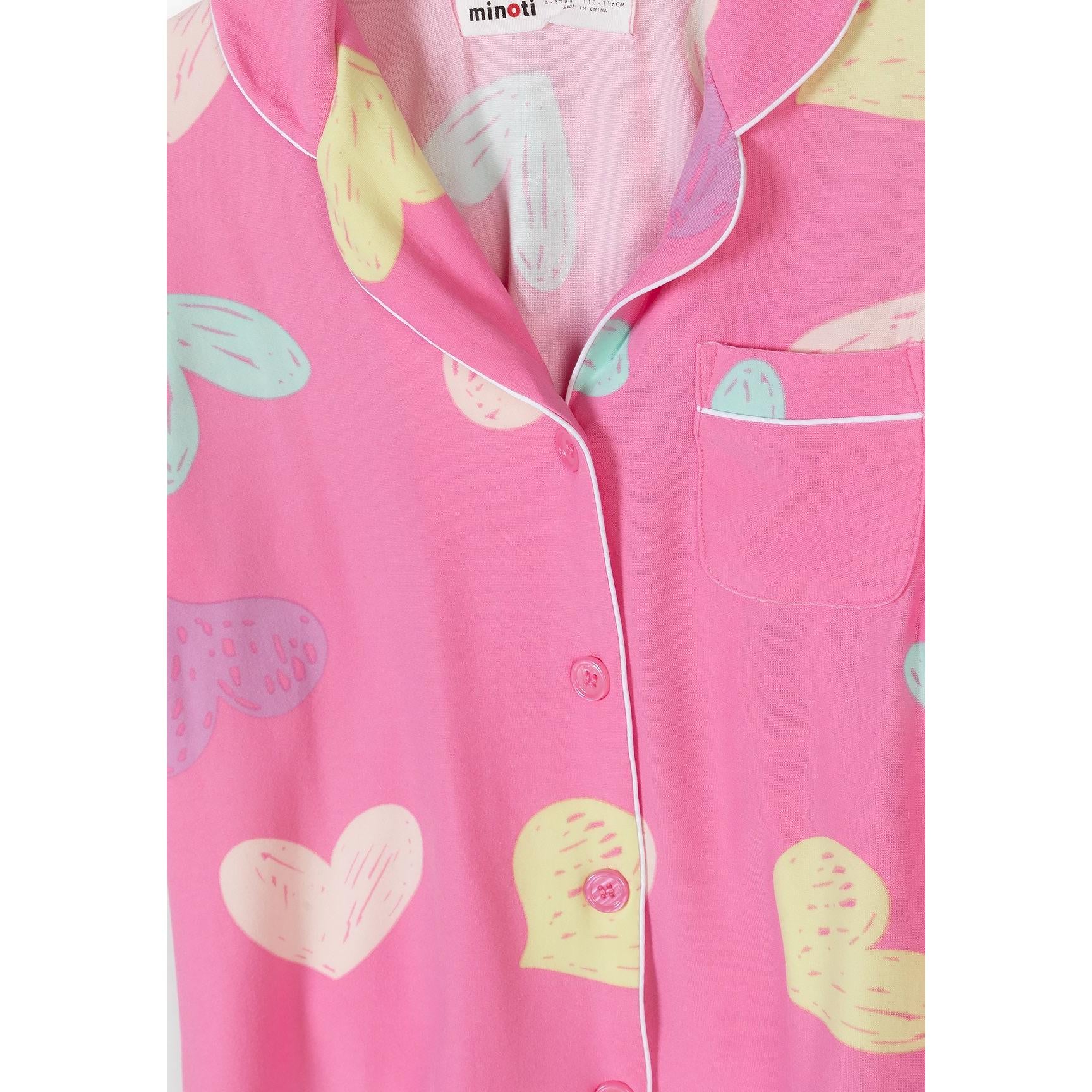 Close-up detail of pink pajama top with colorful heart pattern and white piping trim around collar and pocket