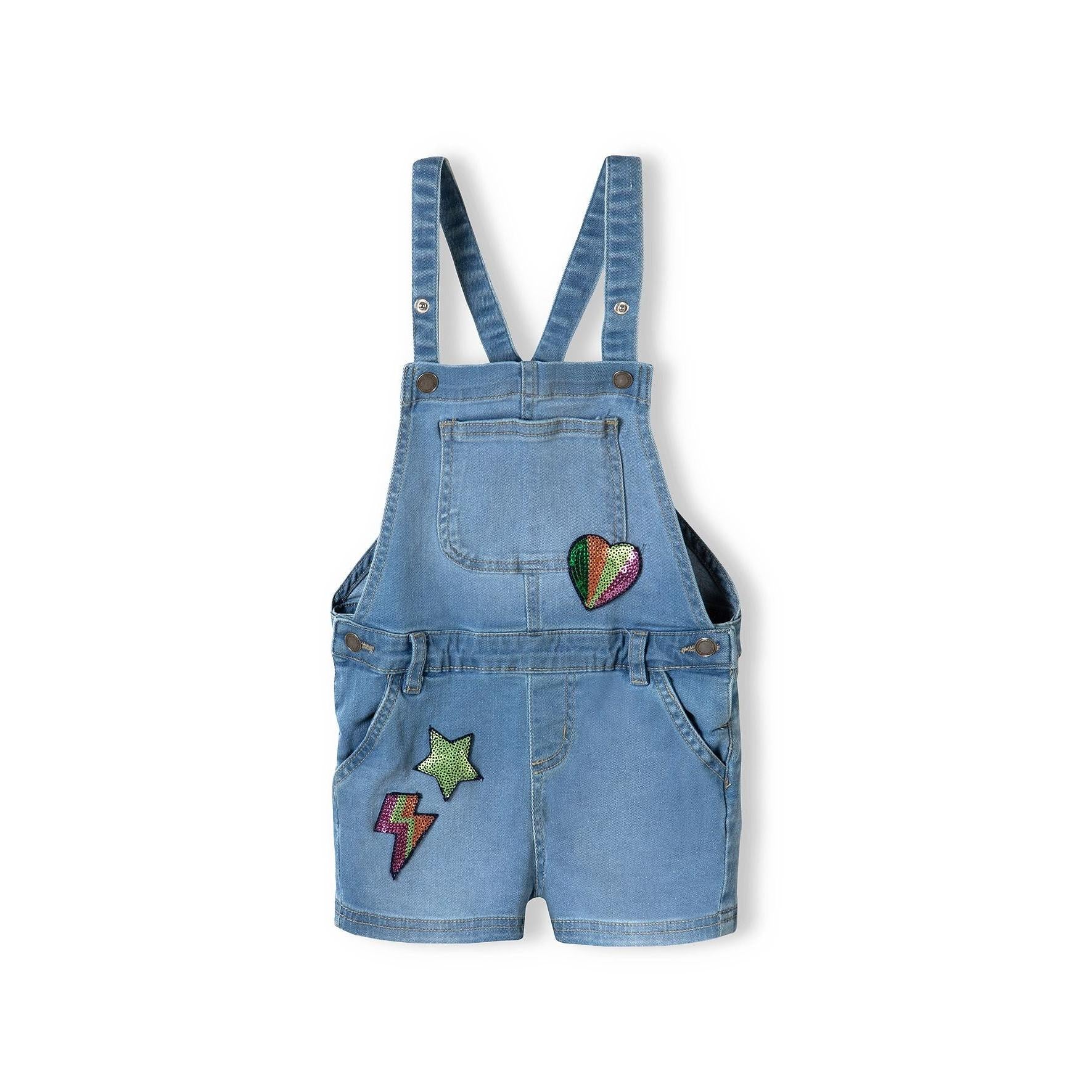 Back view of light blue denim short dungarees showing adjustable shoulder straps, back pockets and sequin star patch detail