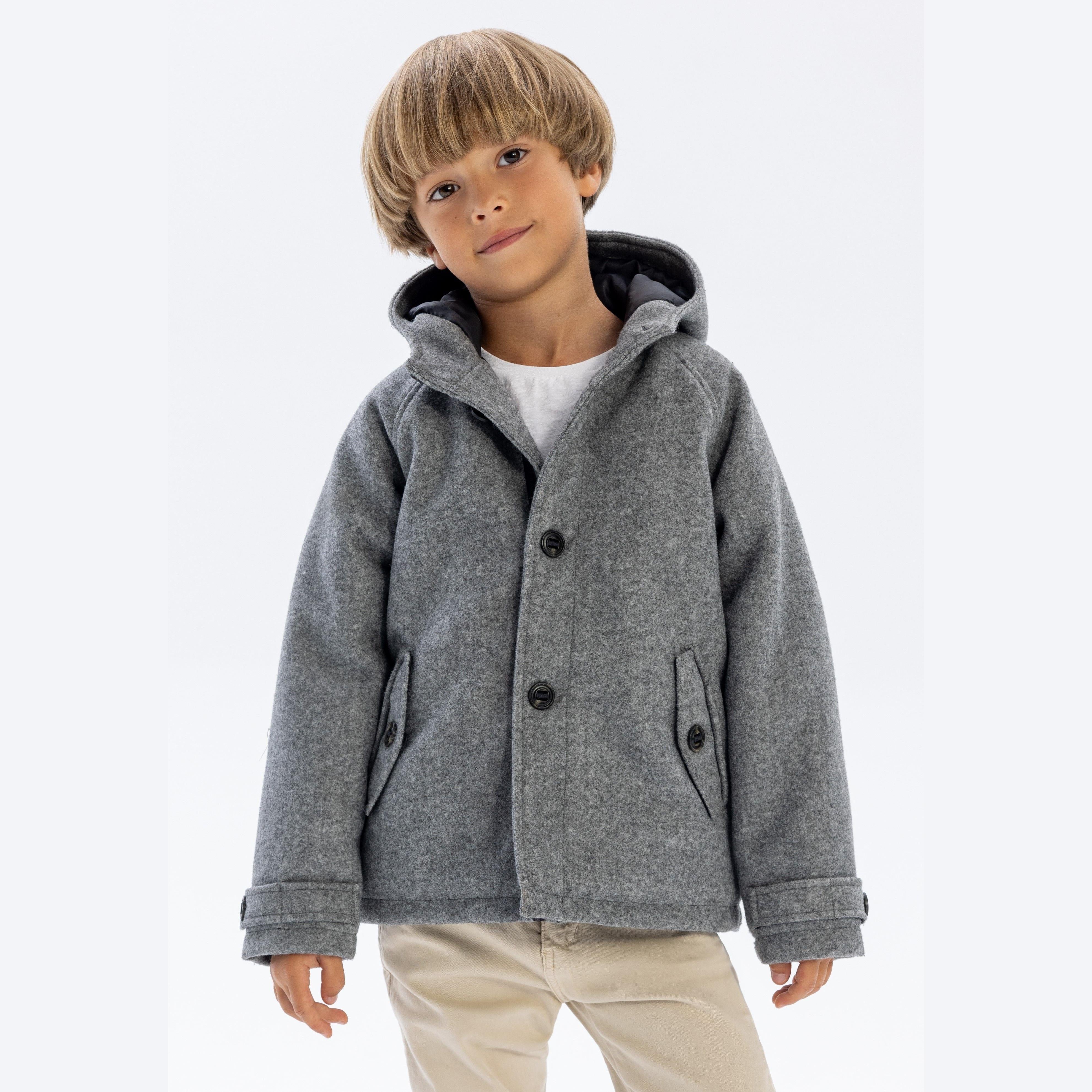 Young boy wearing grey hooded wool coat with button fastening, standing against white background, showing front view of the classic winter coat design