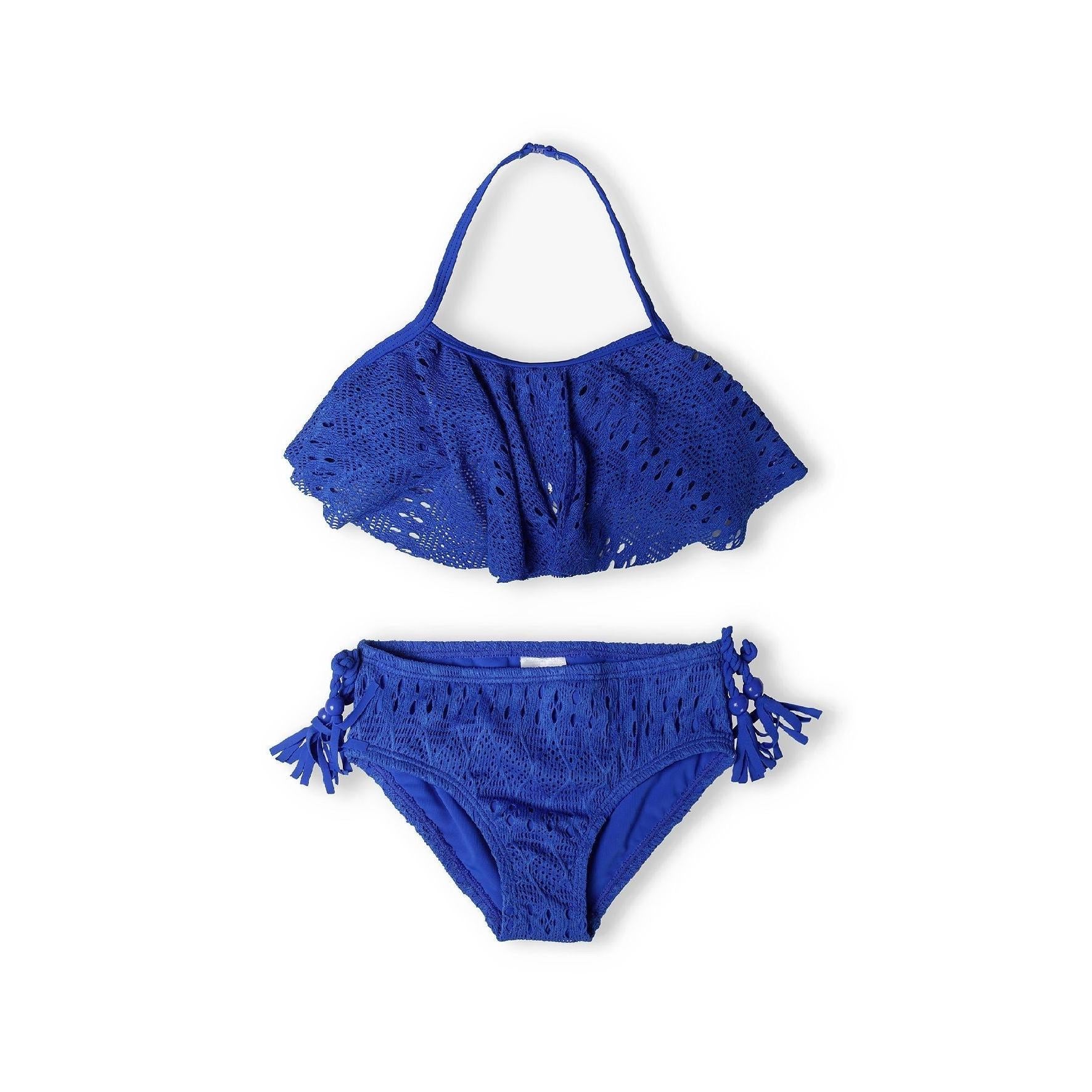 Cobalt blue crochet bikini set laid flat on white background showing halterneck bandeau top with ruffle trim and matching bottoms with side tassels