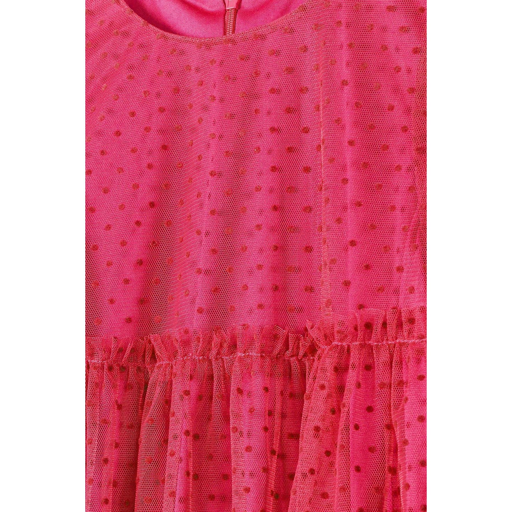 Close-up detail of pink flock printed net fabric showing textured dots pattern and gathered ruffle construction with zip fastening